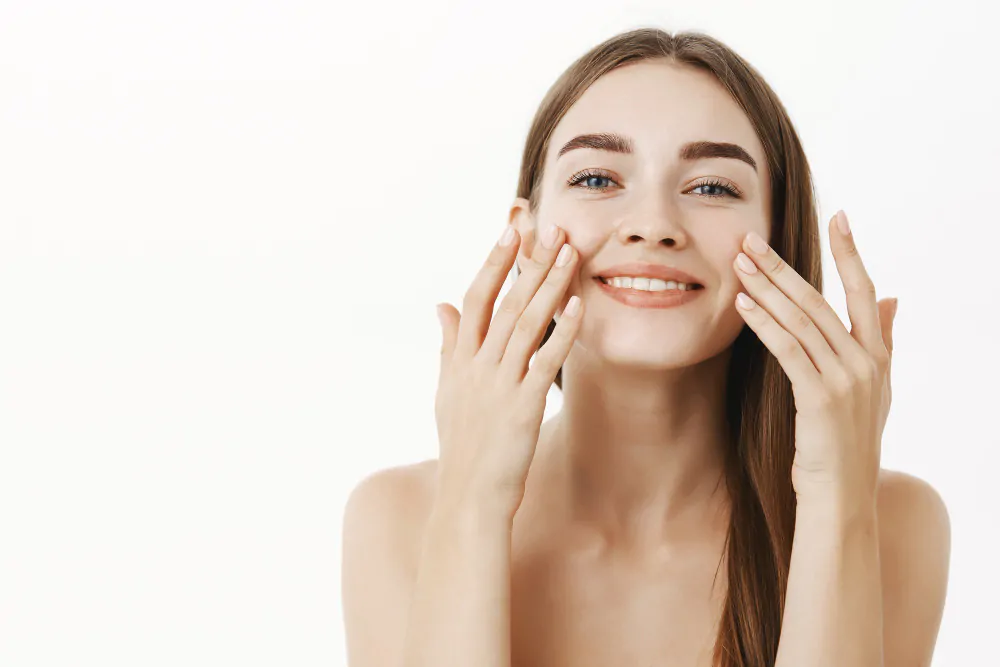 7 dicas de como parecer mais jovem 1 charming relaxed gentle young woman making cosmetological procedure applying facial cream face with fingers smiling broadly feeling perfect taking care skin 1